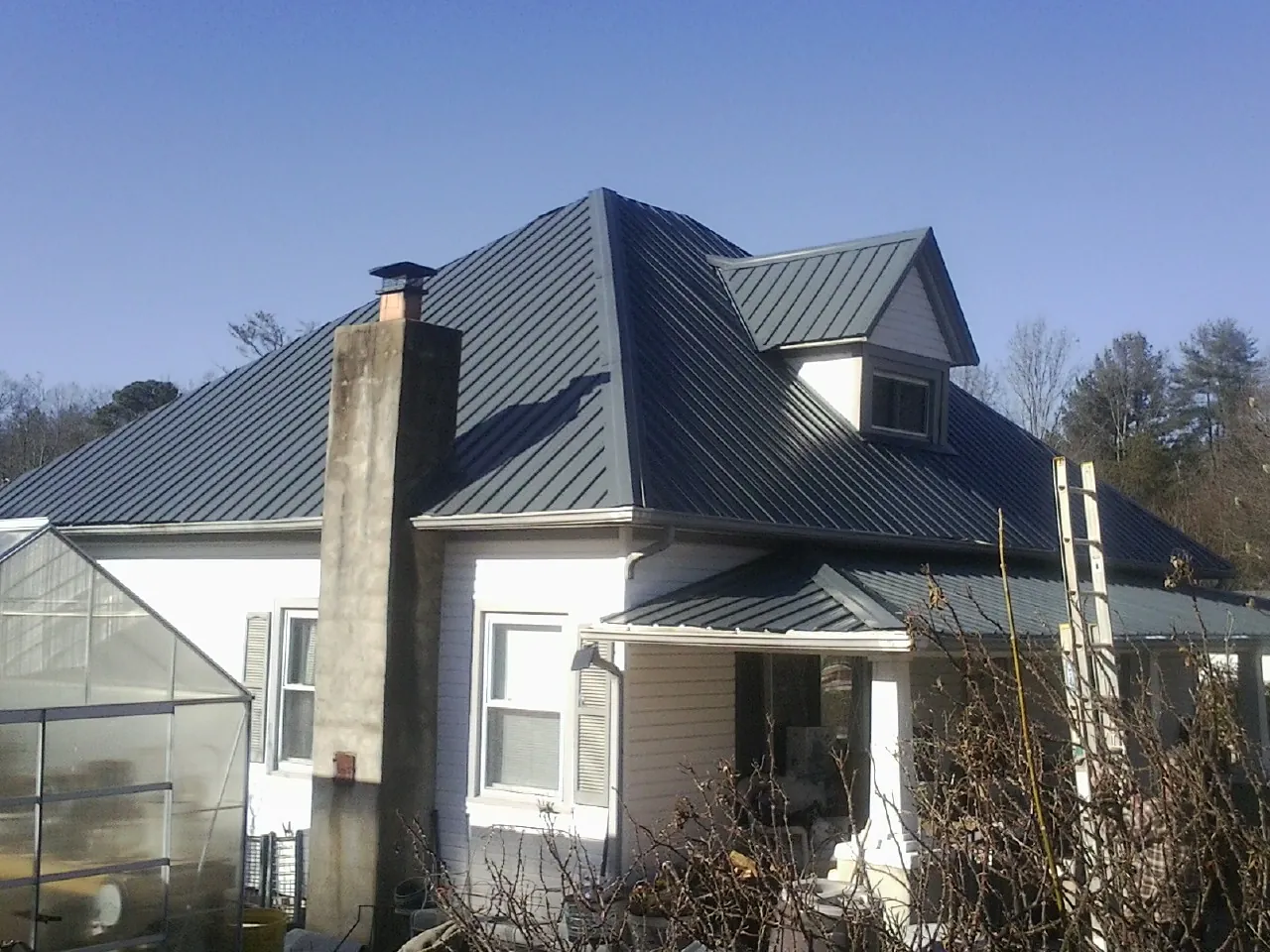 Dark blue standing seam metal roof on a white farmhouse with dormer — Slate & Tile Roof Repair by Roofing Brothers in Palo Alto