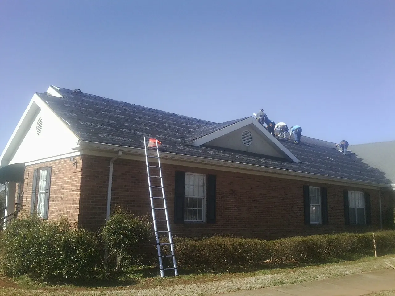 Crew tearing shingles off a brick ranch roof with a ladder set — Metal Roof Repair work by our crew in Palo Alto