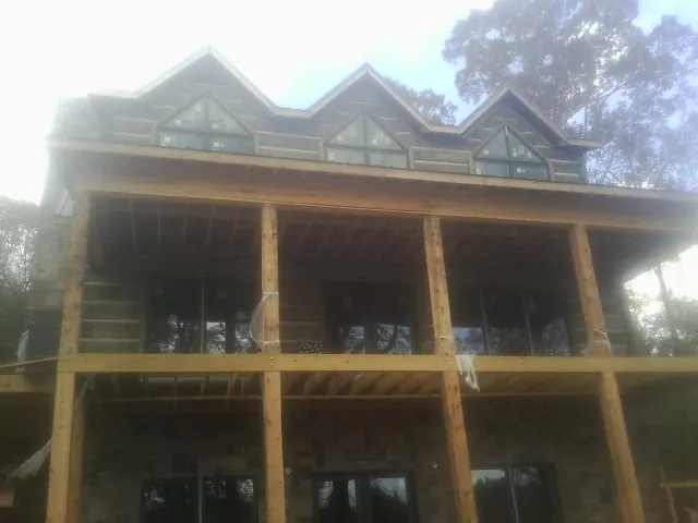 Dormers and porch framing on a large log home under construction — Roof Coating work by our crew in Palo Alto