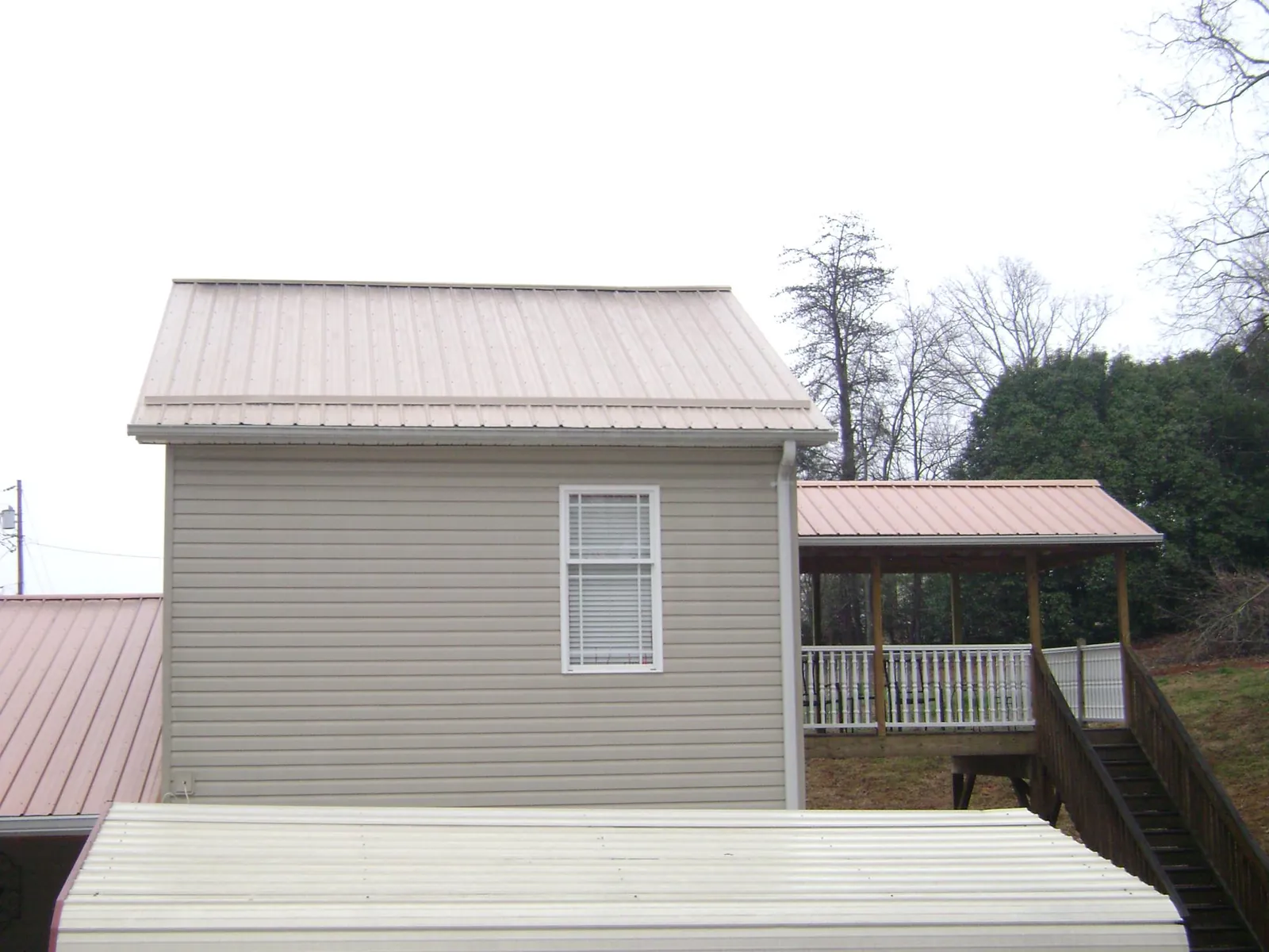 Tan metal roofs on a two story addition and attached porch, from a Roof Replacement job in Palo Alto