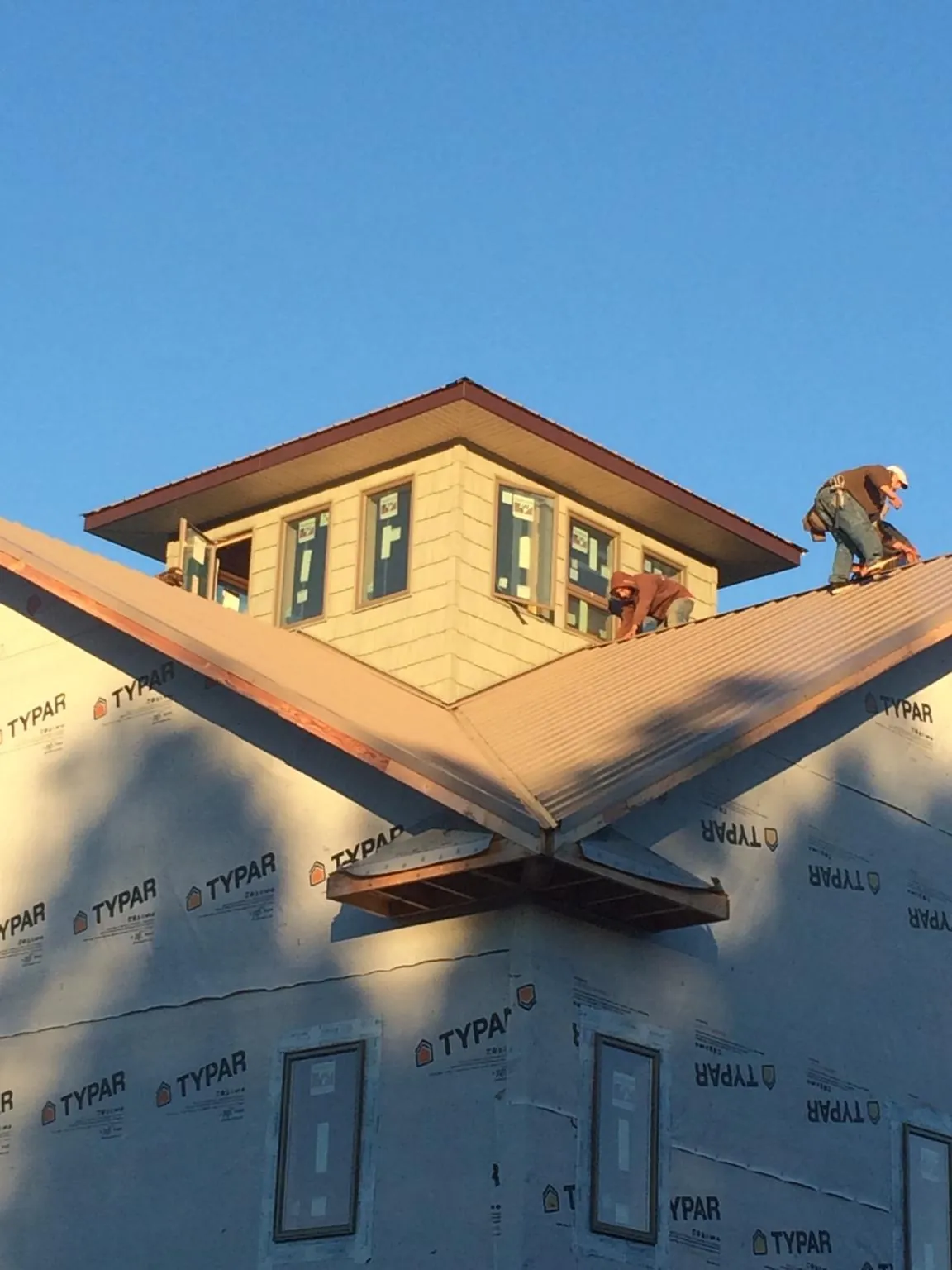 Roofers working around a rooftop cupola on a new metal roof at sunset — Roof Waterproofing in Palo Alto by Roofing Brothers